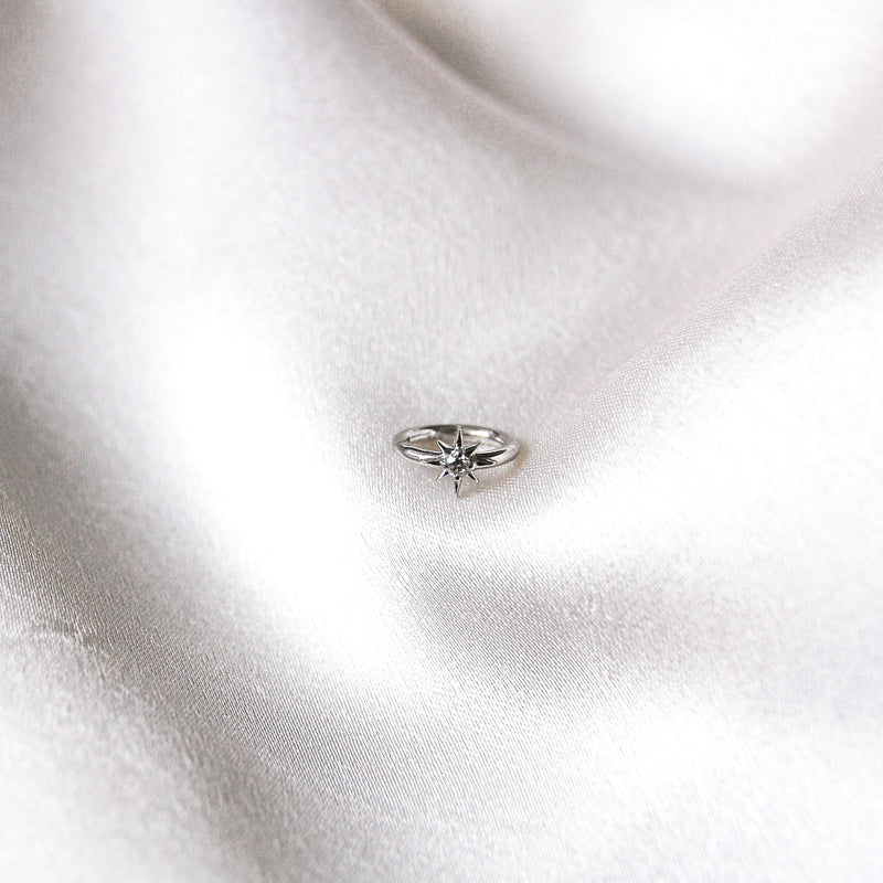Diamond North Star Seamless Huggie Hoop Earring White 9k Gold on sof fabric