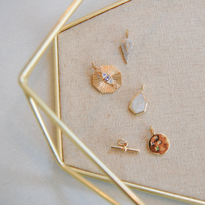 gold pendants in jewellery tray including the Tanzanite, Moonstone Diamond Engraved Hexagon Pendant 9k Gold