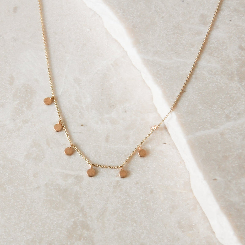 Mini Coin Necklace 9k Gold on marble surface
