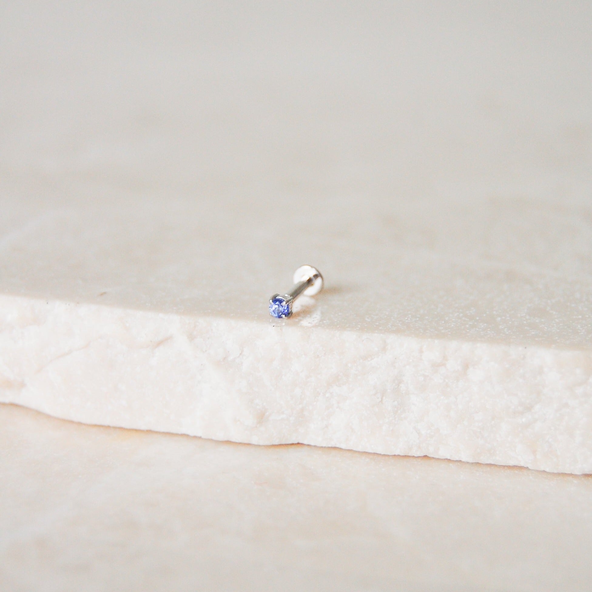 Mini Tanzanite Solitaire Flat Back Earring 14k White Gold on marble surface