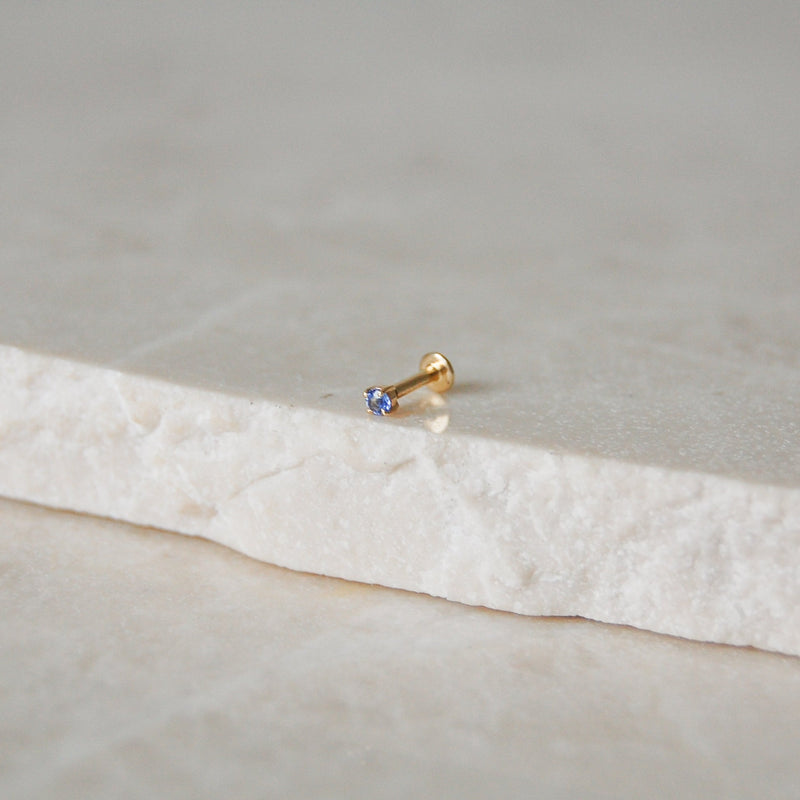 Mini Tanzanite Solitaire Flat Back Earring 9k Gold on marble surface