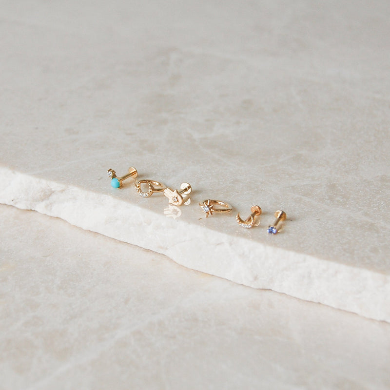 gold earring display on marble surface including the Turquoise & Diamond Flat Back Earring 9k Gold