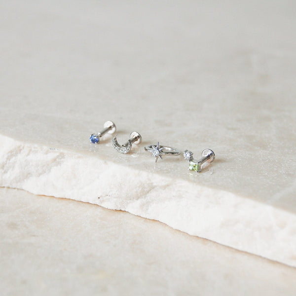 white gold earring display on marble surface including the Mini Tanzanite Solitaire Flat Back Earring 14k White Gold