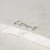 white gold earring display on marble surface including the Diamond North Star Seamless Huggie Hoop Earring White 9k Gold