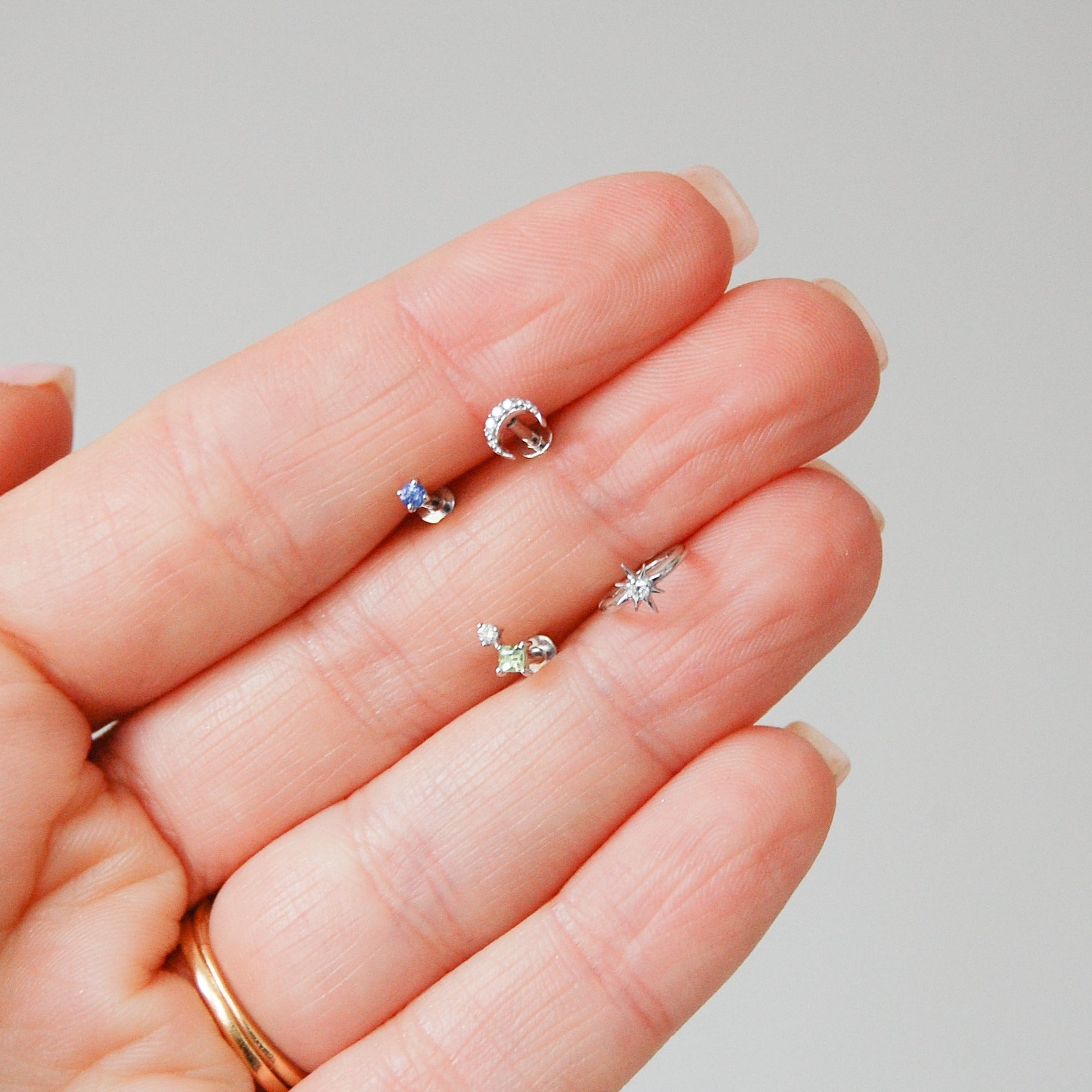 model hand showing a few white gold earrings including the Diamond Moon Flat Back Earring 14k White Gold