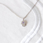 amethyst hand of fatima pendant silver on white fabric