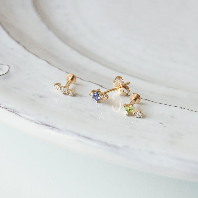 three gold earrings on porcelain dish featuring the peridot flat back earring