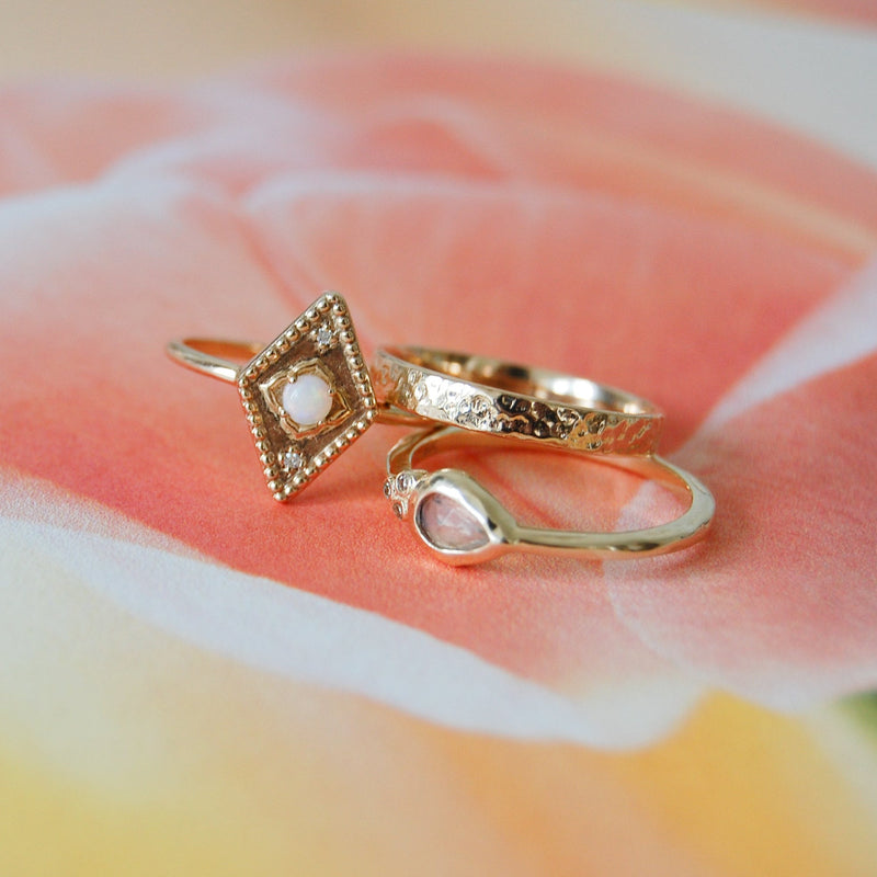 three solid gold rings on floral surface including the Moonstone & Diamond Tear Drop Ring 9k Gold