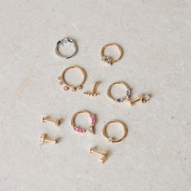 a display of different gold earrings including a diamond solitaire 14k gold hoop for daith piercings