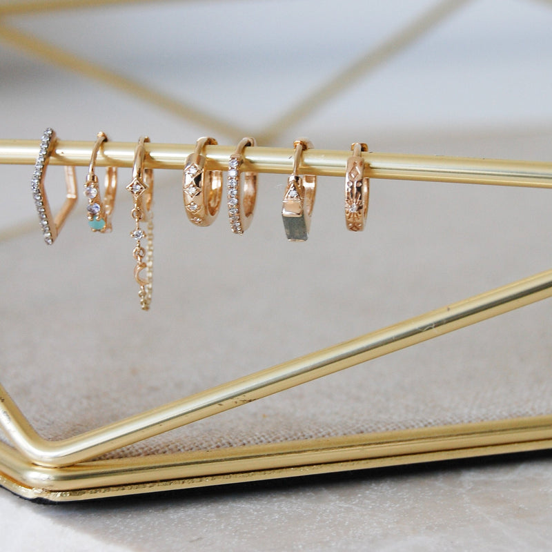 gold and diamond hoops hanging from jewellery tray bar including the Diamond Starburst Huggie Hoop Earring 9k Gold