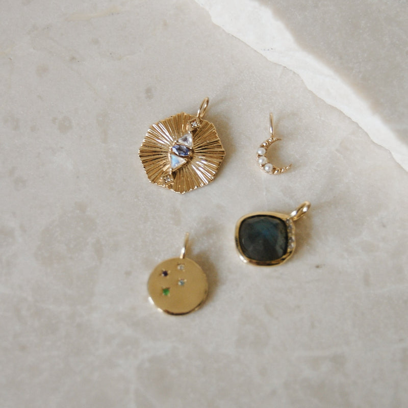 Gold Necklaces on marble surface, including the Mini Pearl Moon Pendant 9k Gold