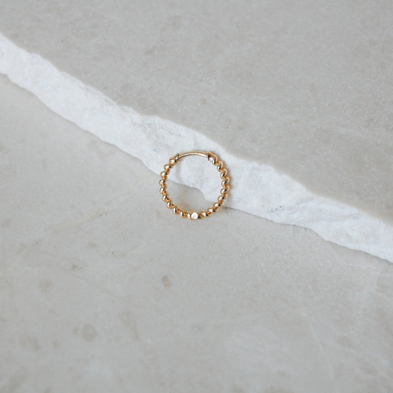 Medium Twisted Huggie Hoop Earring 9k Gold on marble surface