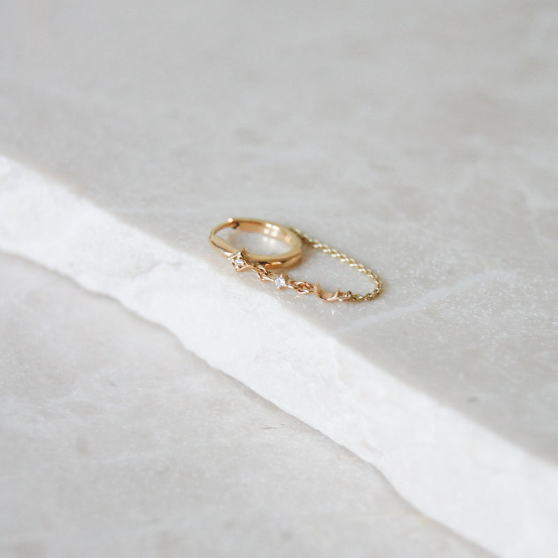 Diamond Moon Chain Huggie Hoop Earring 9k Gold on marble surface