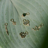 solid gold earring charms displayed on a green leaf including the Labradorite & White Sapphire Earring Charm 9k Gold