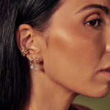 model wearing gold huggies and charms including the Diamond Paisley Teardrop Huggie Earrings Pair 9k Gold