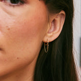 Close-up of a person wearing a gold hoop earring.