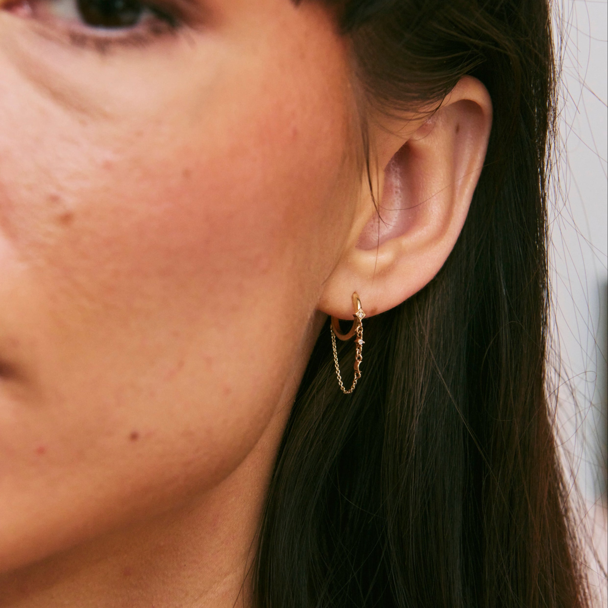 Close-up of a person wearing a gold hoop earring.