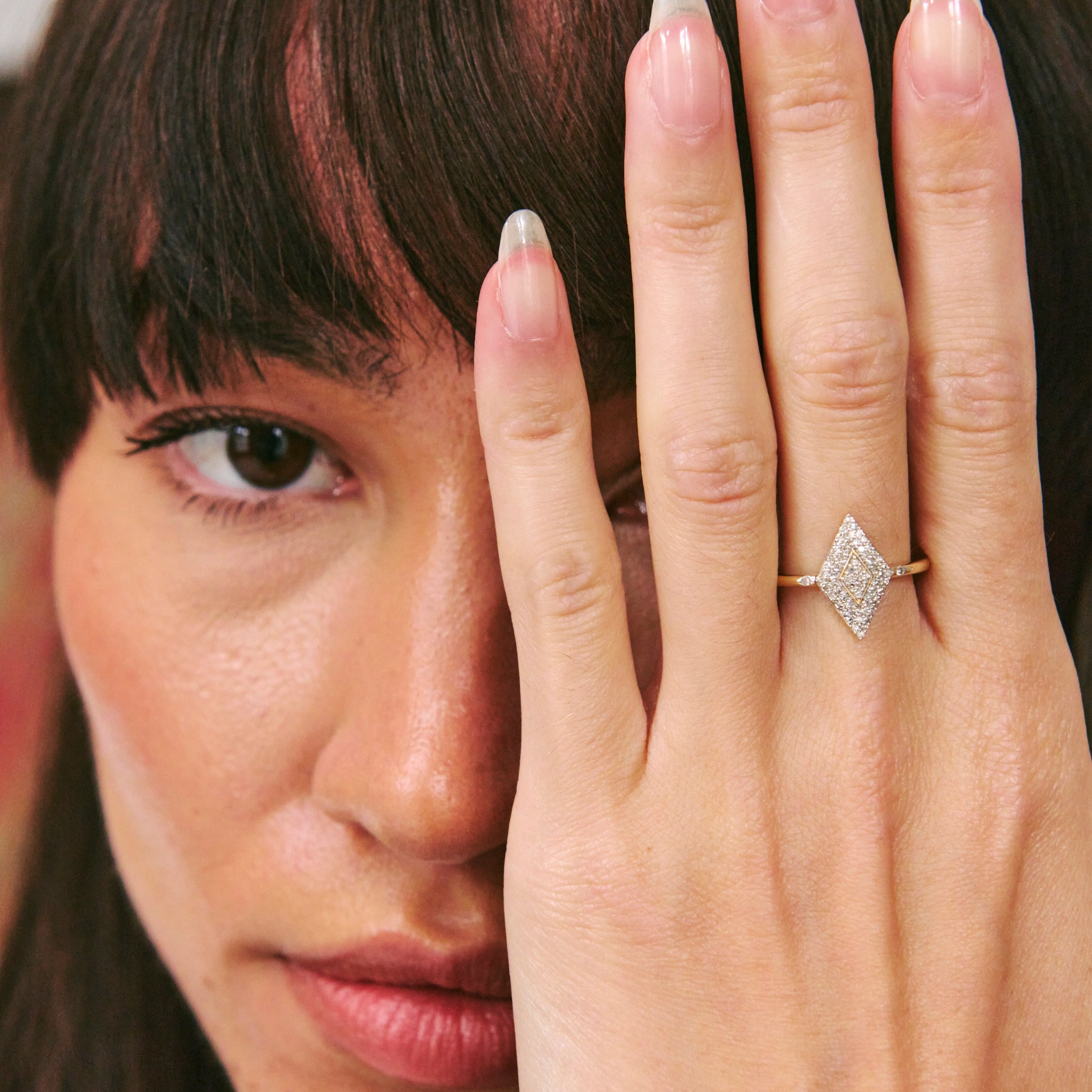 Woman wearing a diamond ring on her hand, with a blurred background