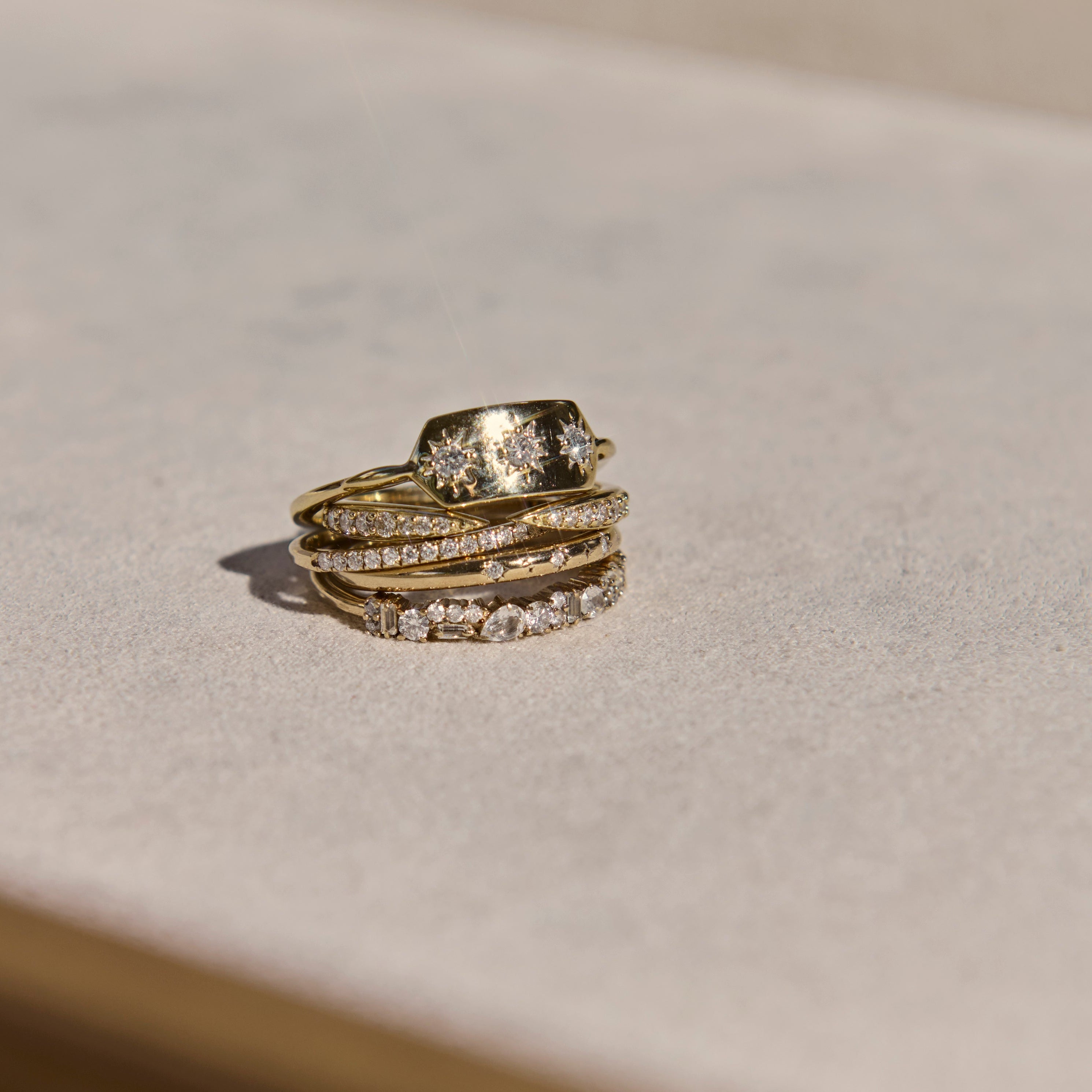 Stack of gold and diamond rings on a light background