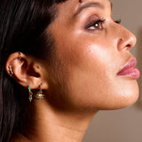 model wearing solid gold earrings including the Emerald & Diamond Marquise Huggie Hoop 9k Gold