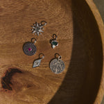 Five silver pendants on a wooden surface