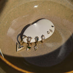 Set of gold earrings with various gemstones on a white stone surface.