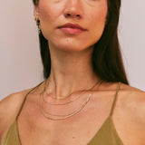 Woman wearing a gold necklace with a plain background