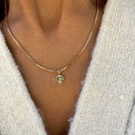 Gold necklace with a pendant worn by a person in a white sweater.