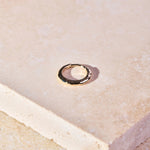 Hammered Huggie Hoop Earring 9k Gold on hard surface