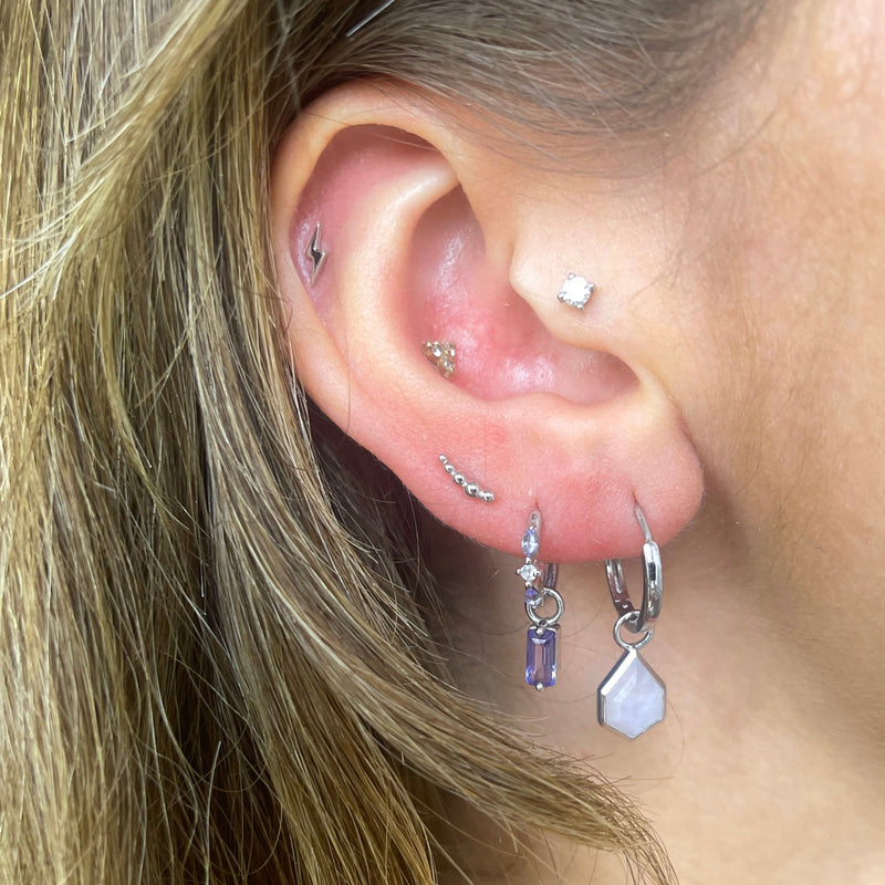 model wearing white gold and silver earring stack including the graduated bead flat back earring 14k white gold on upper lobe