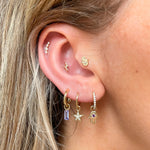 model wearing gold earring stack including the hand of Fatima earring charm 9k gold in diamond hoop