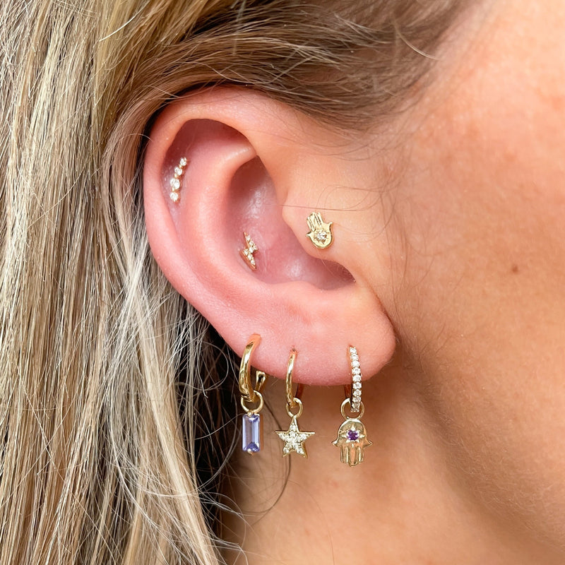 model wearing gold earring stack including the hand of Fatima earring charm 9k gold in diamond hoop