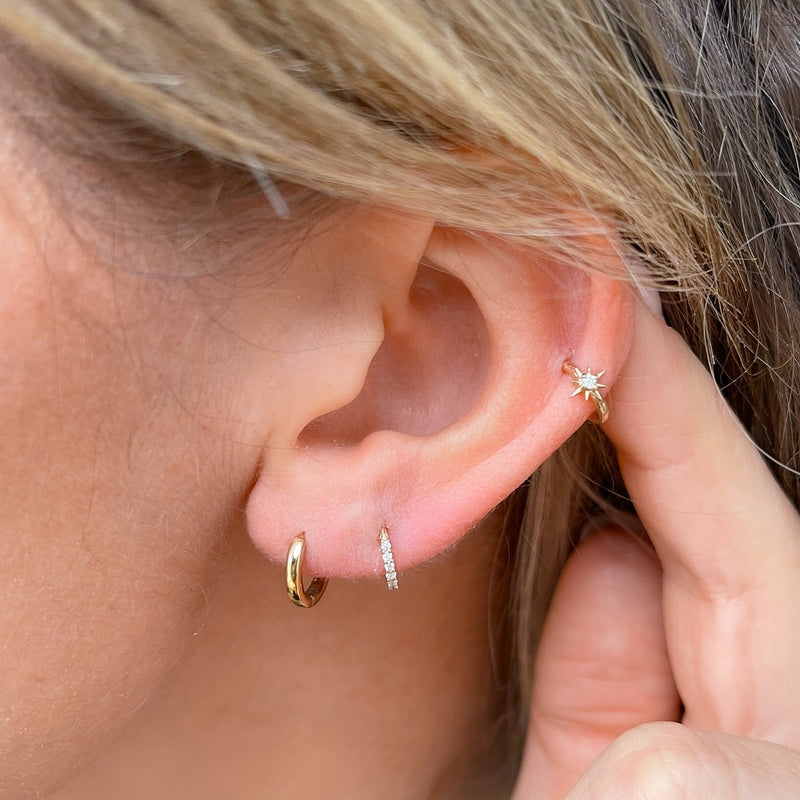 model wearing the Diamond North Star Seamless Huggie Hoop Earring 9k Gold on helix