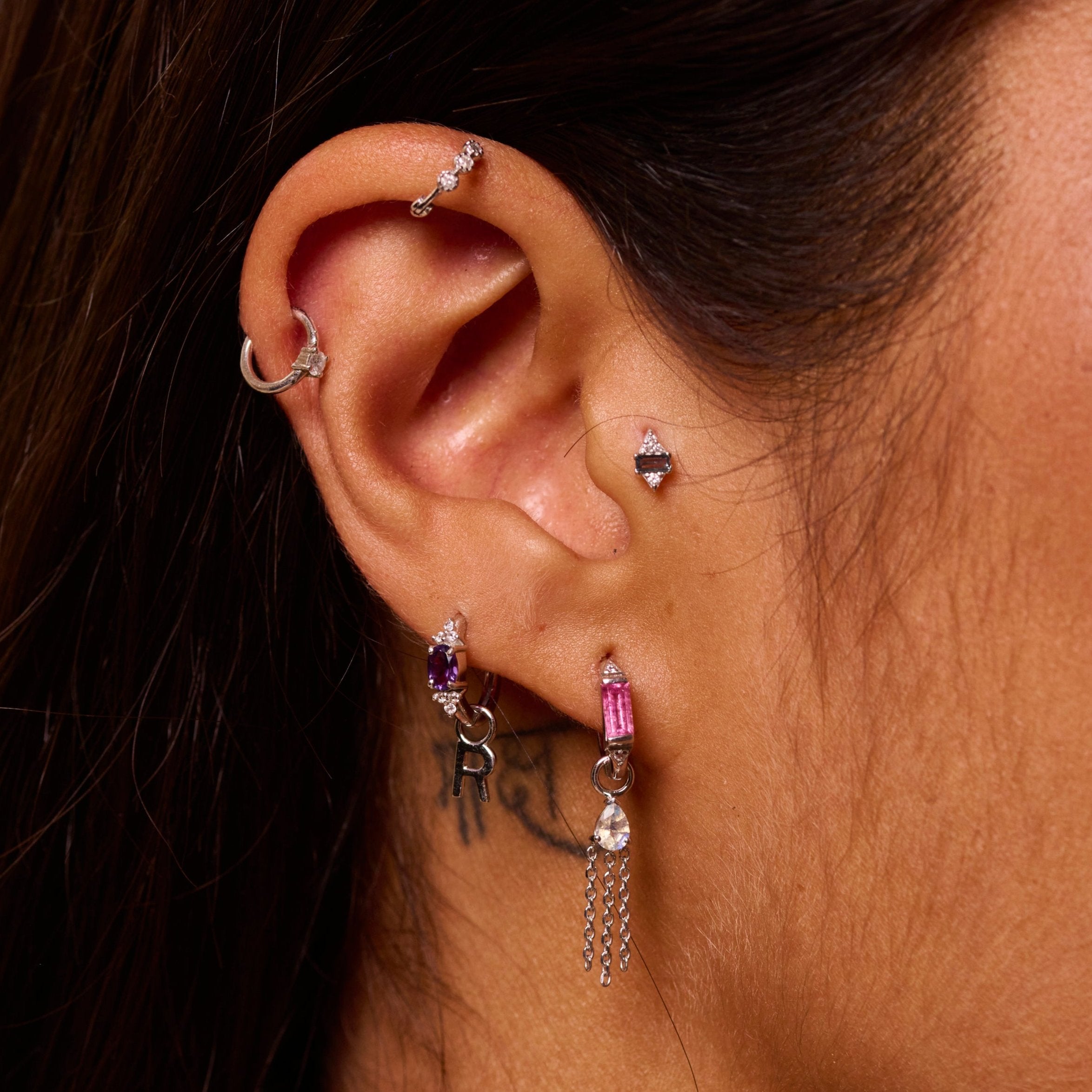 ear close up of sterling silver earring stack including the Initial Earring Charm Sterling Silver