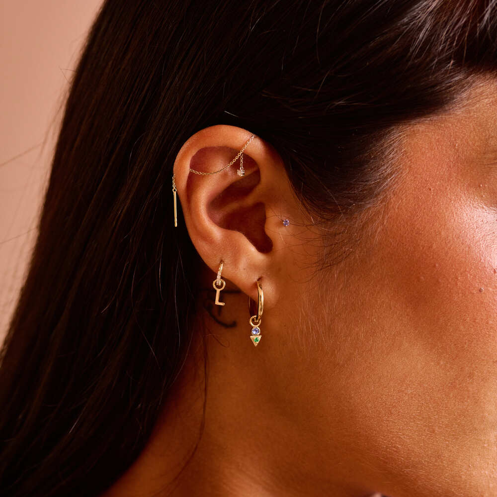 model wearing ear stack including the initial charm in solid gold
