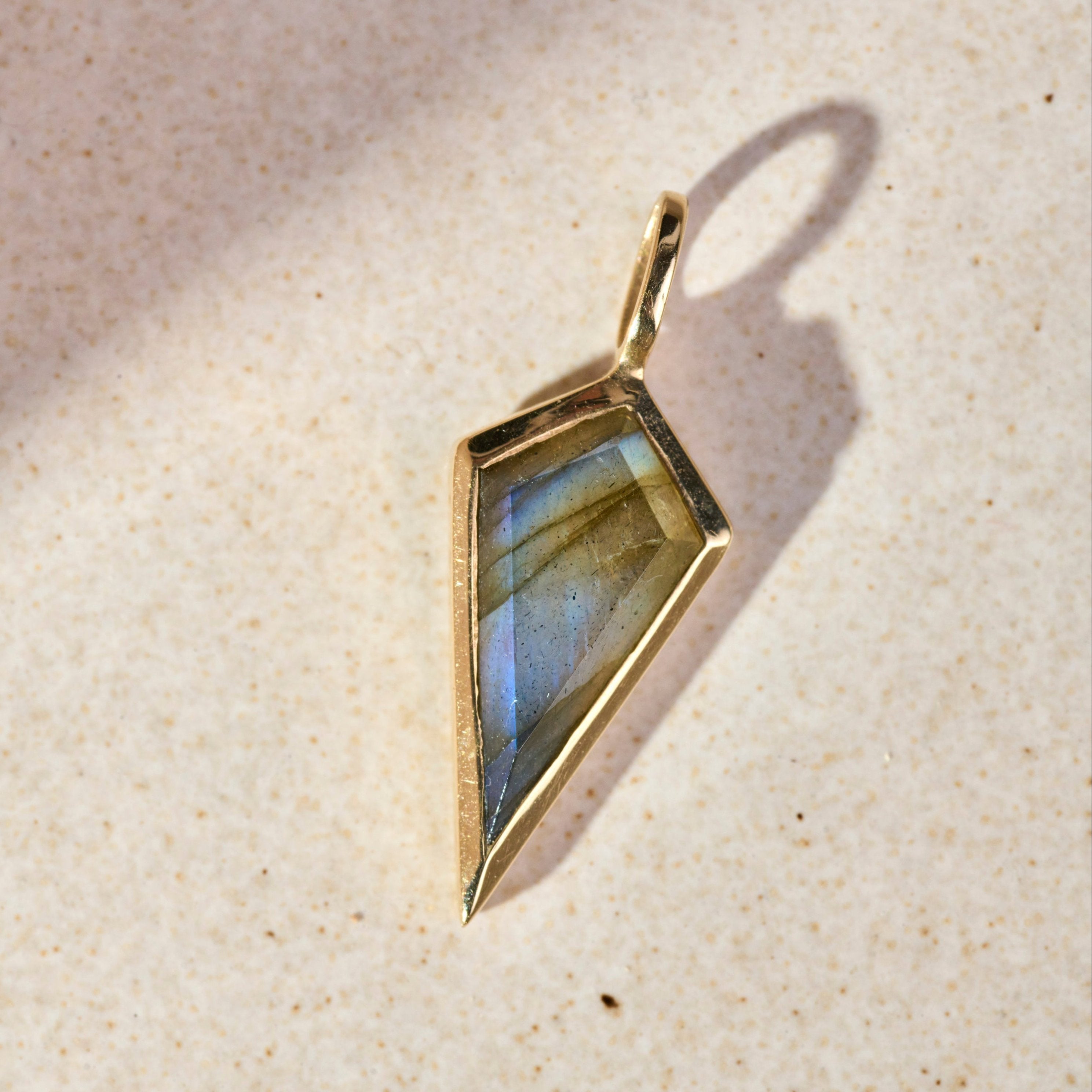 close up of the Labradorite Rhombus Pendant 9k Gold on hard surface