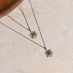 Two necklaces with floral pendants on a beige surface