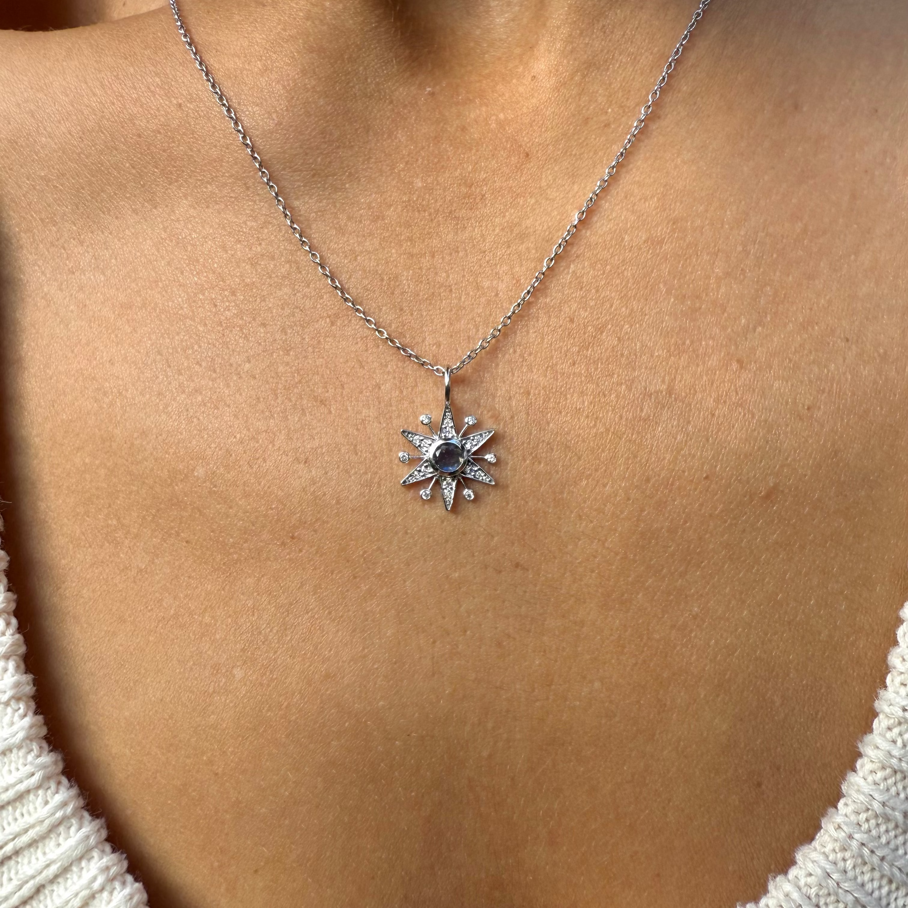 white gold necklace with a star pendant on a person wearing a white sweater.