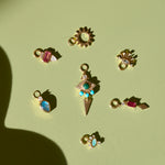 solid gold earring charms on green surface including the Limited Edition Malachite Eye Hoop Earrings 9k Gold