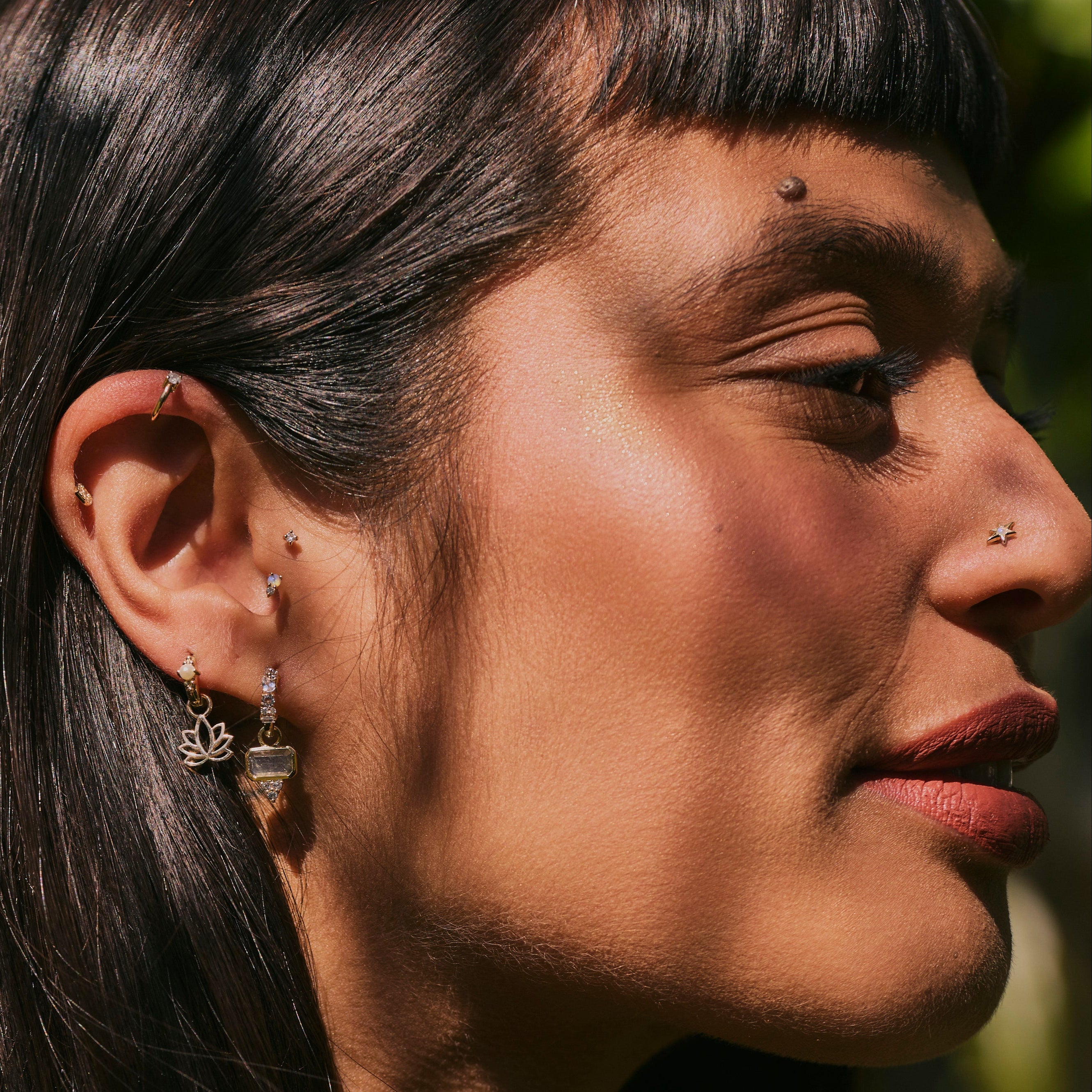model wearing solid gold pieces including the Lotus Flower Earring Charm 9k Gold
