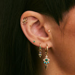 Close-up of an ear with multiple gold earrings featuring gemstones.