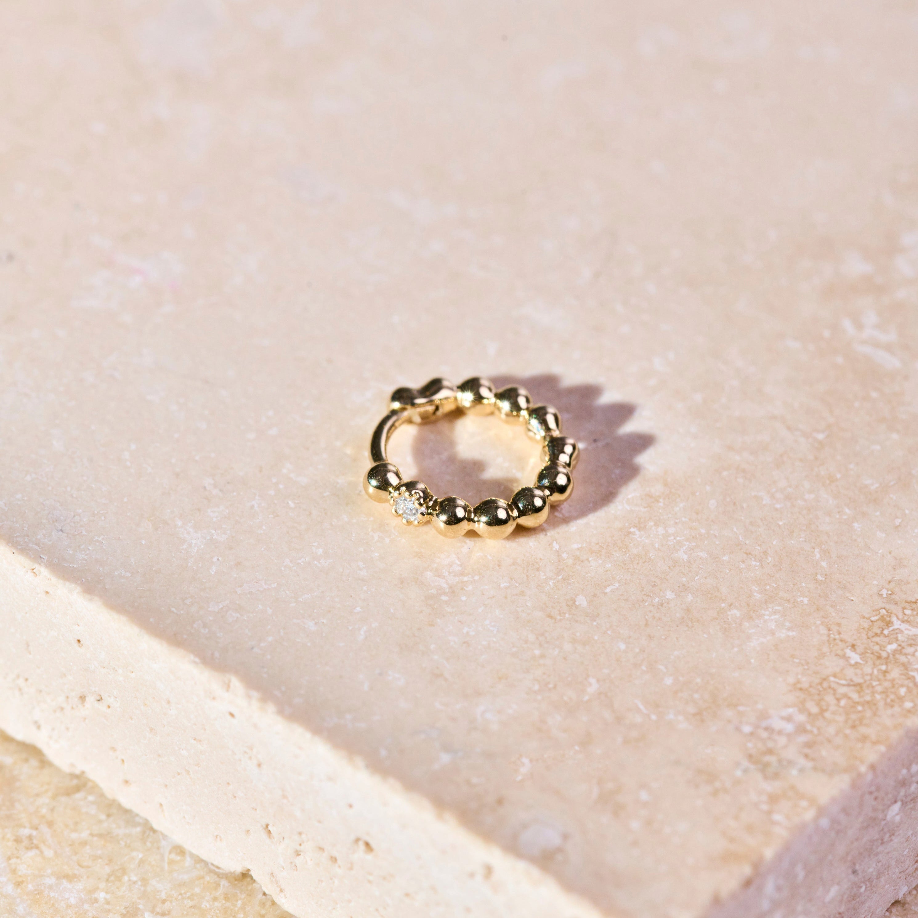 Mini Diamond Beaded Huggie Hoop 9k Gold on hard surface