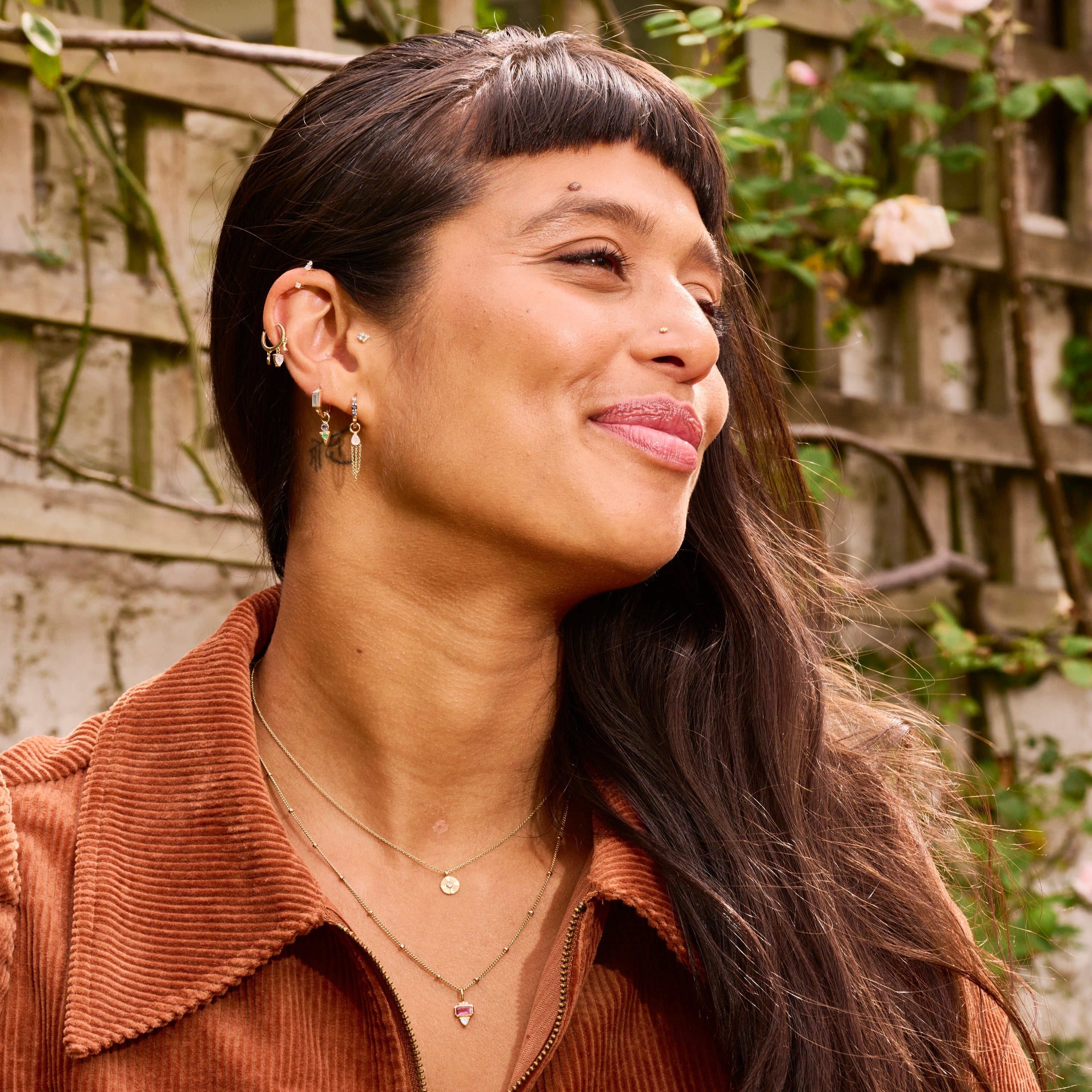 model wearing solid gold earrings and necklaces including the Mini Diamond Coin Pendant 9k Gold