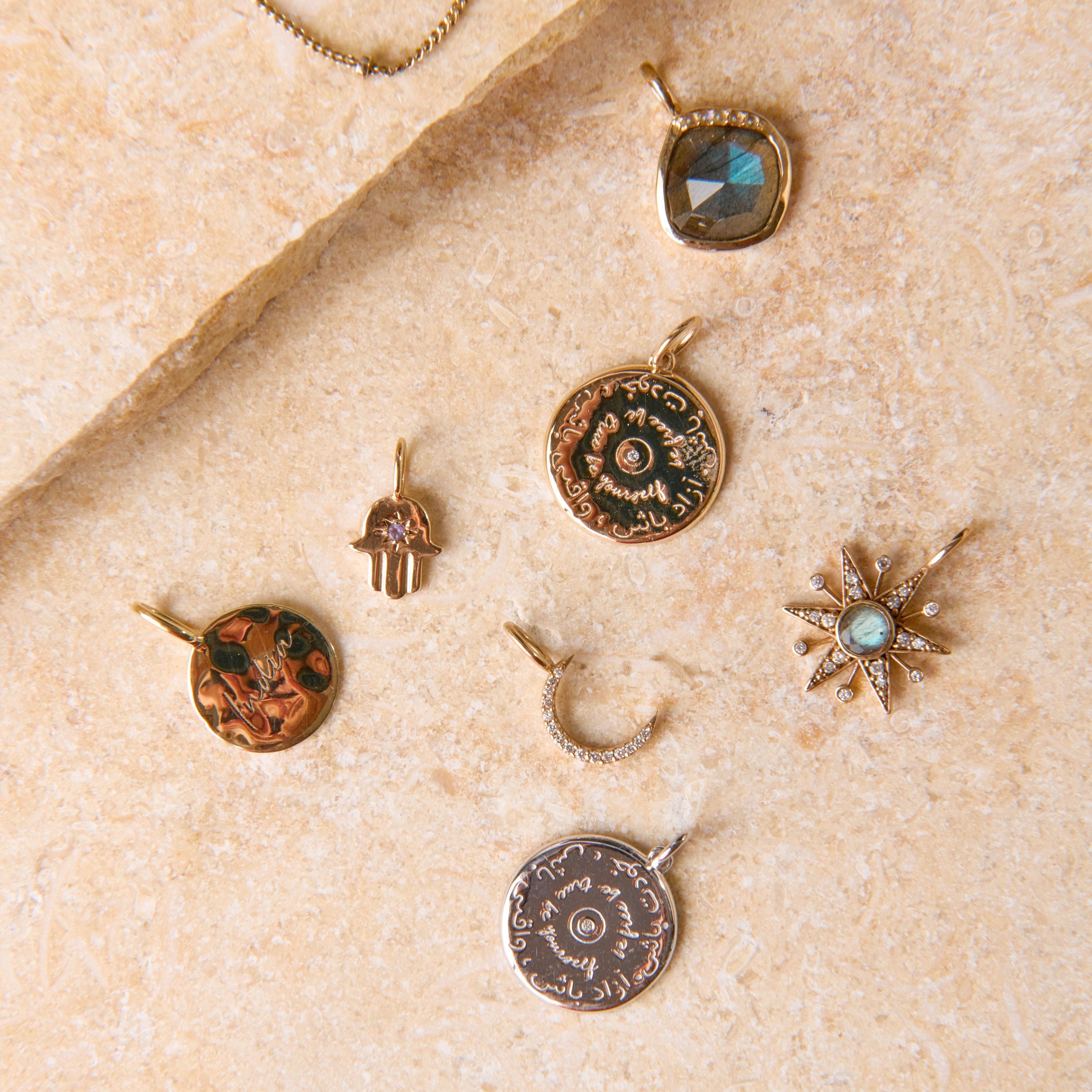 solid gold pendants displayed on hard surface including the Mini Diamond Moon Pendant 9k Gold