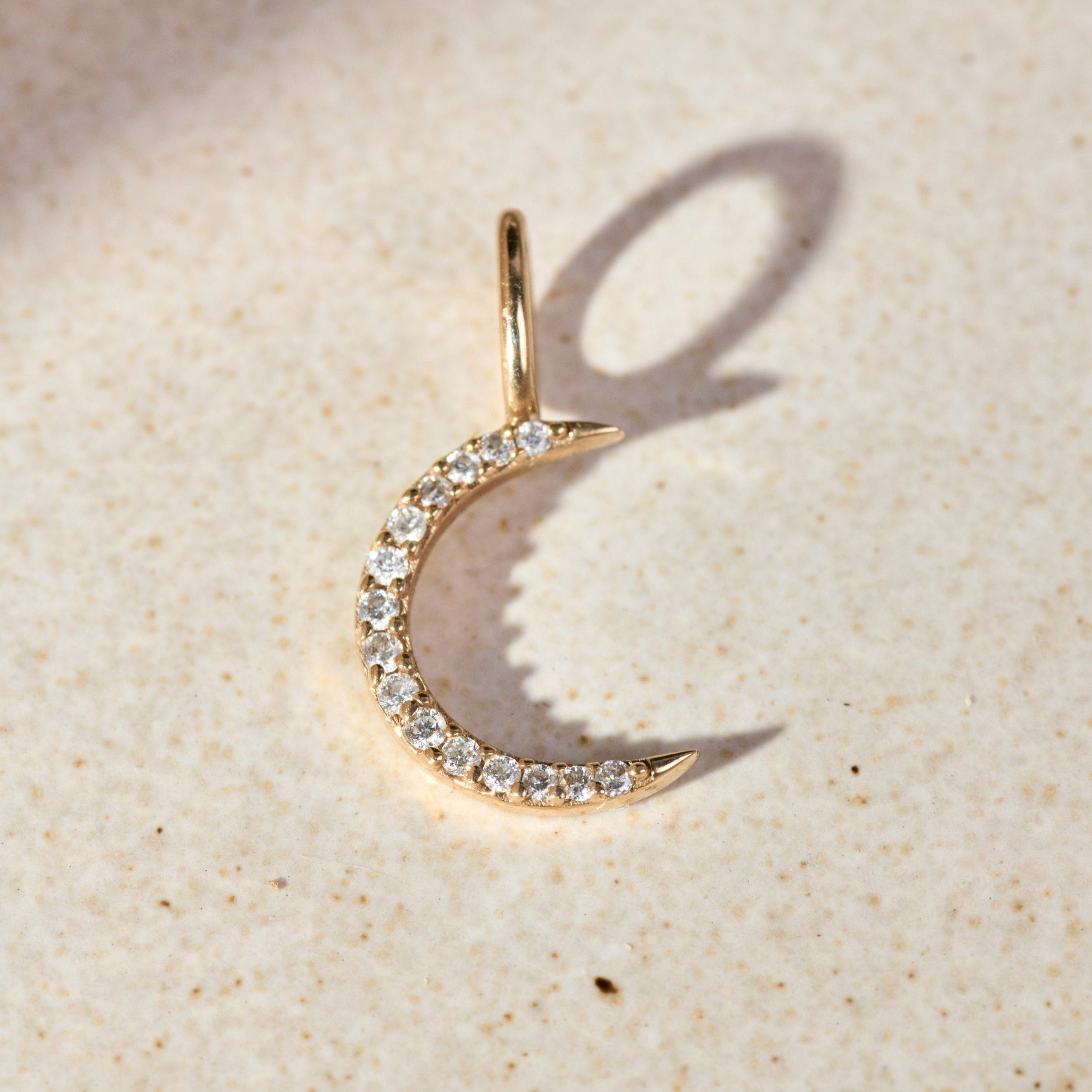 close up of the Mini Diamond Moon Pendant 9k Gold on hard surface