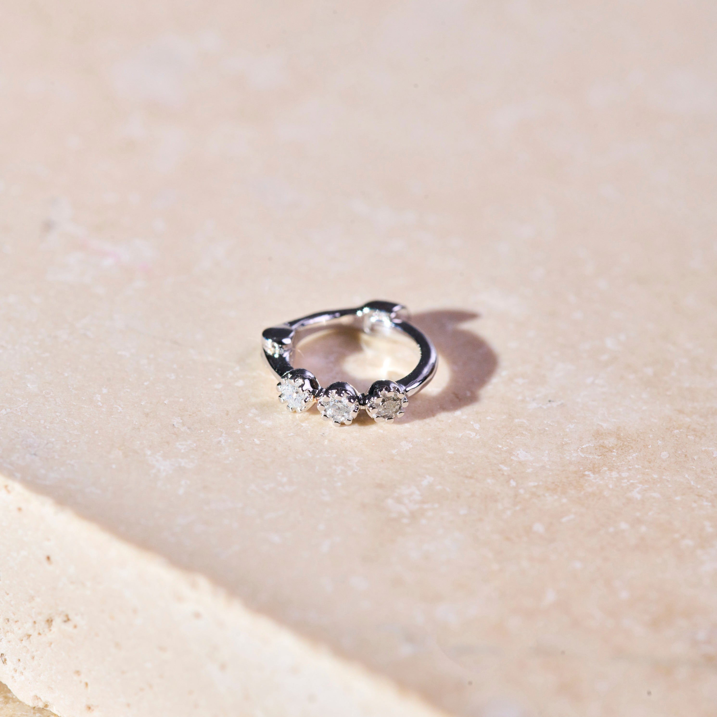 Mini Diamond Trilogy Huggie Hoop Earring Sterling Silver on hard surface
