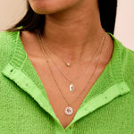 mode wearing the Moonstone & White Sapphire Sunburst Necklace 9k Gold layered with other solid gold pieces