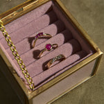 Three rings with gemstones in a jewelry box on a textured surface