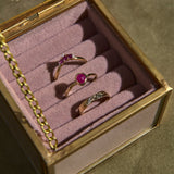 Three rings with gemstones in a jewelry box on a textured surface