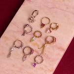 Fine jewellery displayed on hard surface including the Pink Tourmaline, Diamond & Topaz Daith Hoop 9k Gold